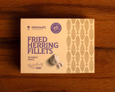 A  tin of herring fillets in cream-coloured packaging with purple lettering by a picture of a garlic bulb and two garlic cloves.