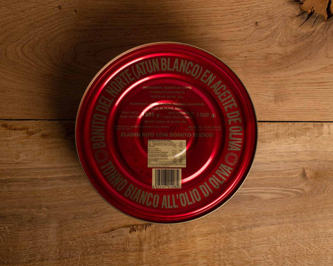 A large circular tin of tuna. The lid is red with gold lettering round the sides.