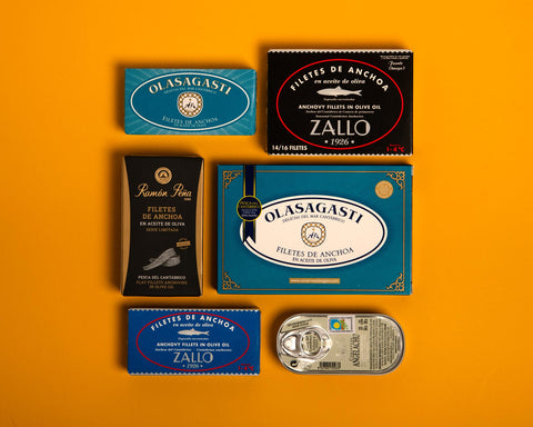 six traditional anchovies packaged in traditional designs against a yellow background